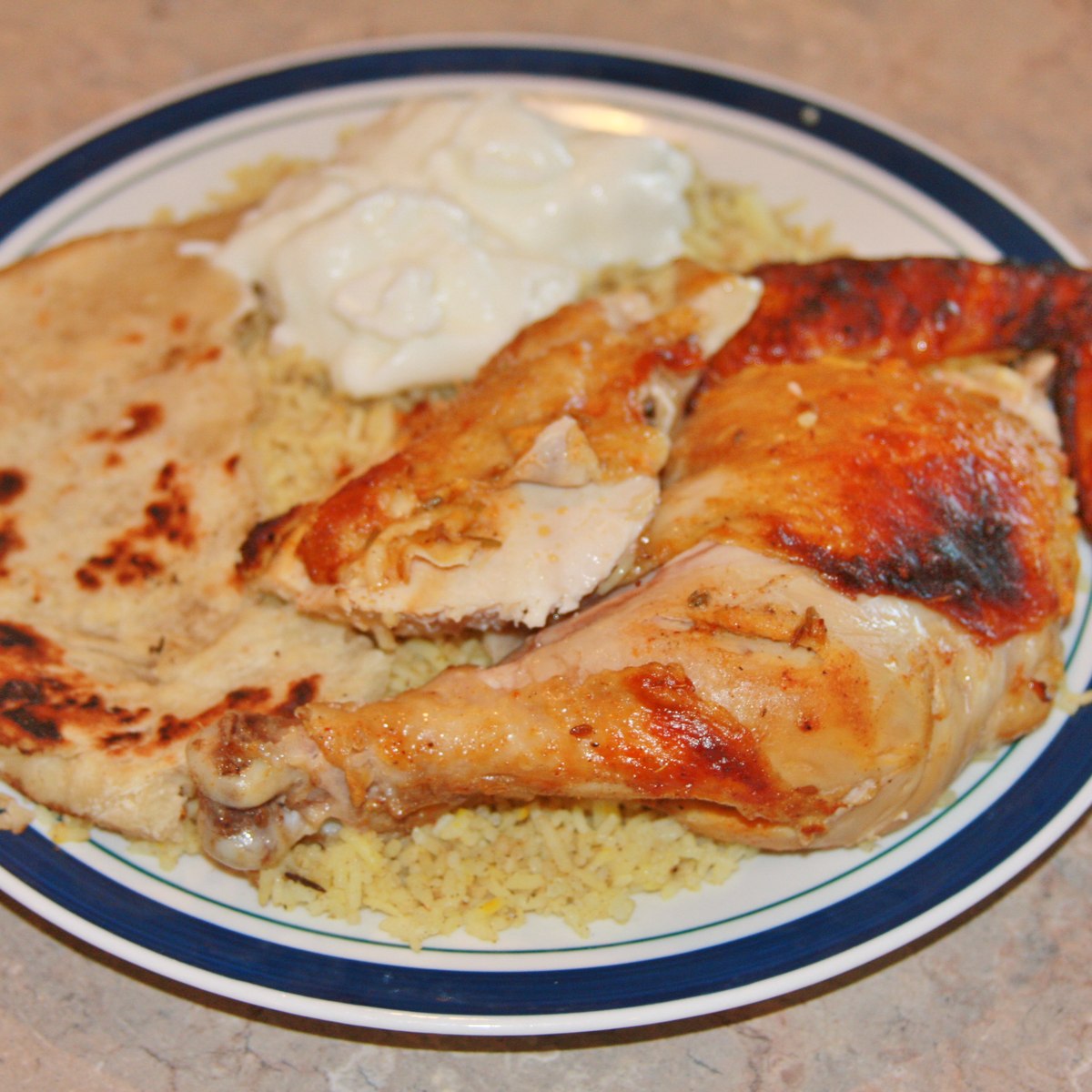Charred tandoori chicken plated with naan, rice and raita